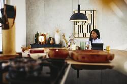 Man looking serious, sitting at a kitchen table with tablet.