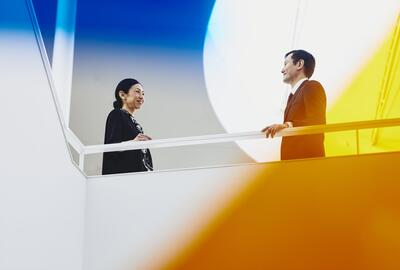 Man and woman talking. Japan. Primary color: yellow.